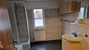 A bathroom with a shower, a sink, and a window.