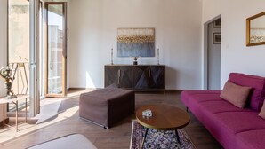 Un salon moderne avec une grande fenêtre, un canapé, une table basse et un meuble.