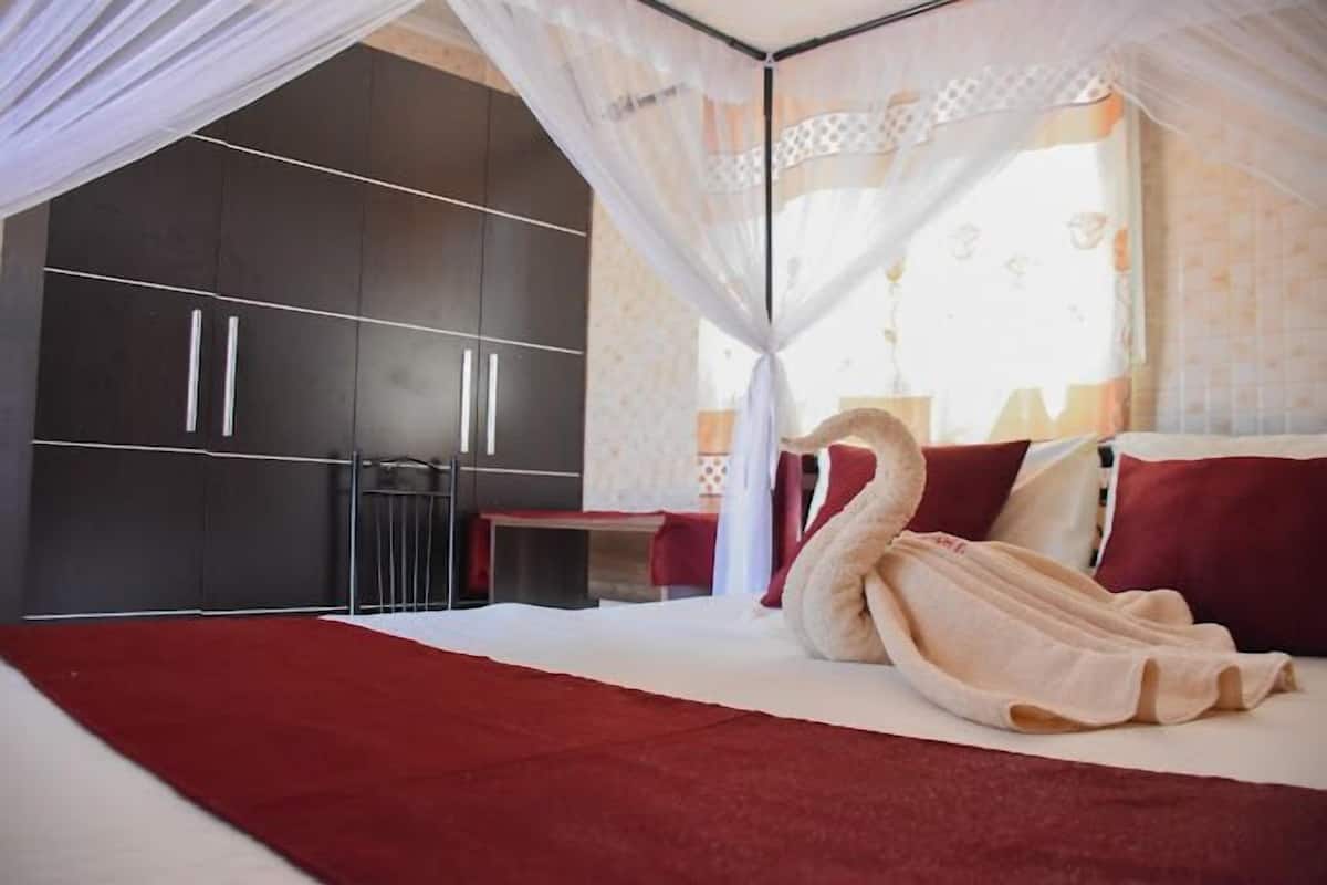 Ein Schlafzimmer mit einem großen Bett, einem roten Teppich, einem Himmelbett und einem Kleiderschrank.