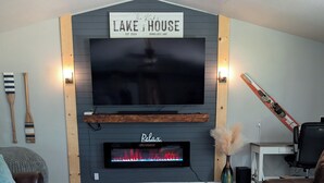 A living room with a fireplace, a mounted TV, and two leather sofas.