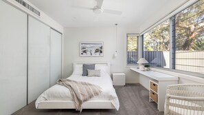 Un dormitorio moderno con cama, mesita de noche, escritorio y silla.