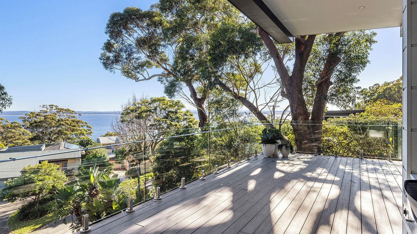 A wooden deck with a view of the sea and surrounding trees.