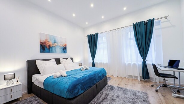 A modern bedroom with a large bed, a desk, and a laptop. - Bright apartment in the heart of Mönchengladbach (Mönchengladbach)