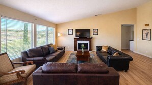 A living room with two sofas, a coffee table, a fireplace, and large windows. - Private Temecula Getaway | Walk to Wineries (Temecula)