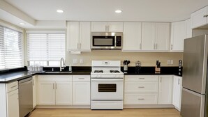 A modern kitchen with white cabinets, a stainless steel refrigerator, a microwave, and a stove. - Private Temecula Getaway | Walk to Wineries (Temecula)