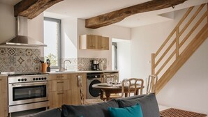 Una cocina moderna con armarios de madera, una estufa de acero inoxidable y un comedor con mesa y sillas de madera.