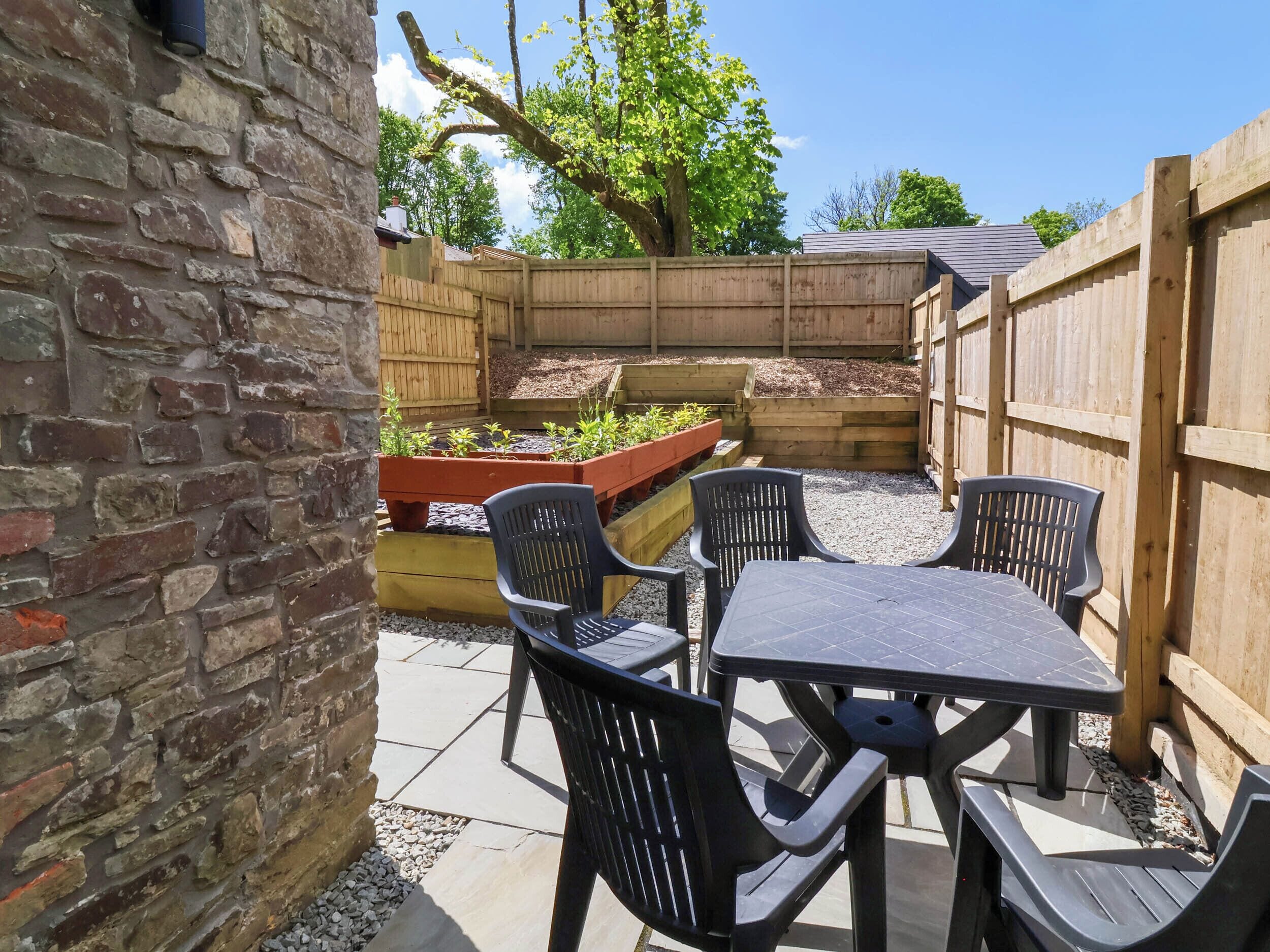 A patio with a table and chairs, surrounded by a brick wall and a wooden fence.