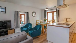 Un salon moderne avec un canapé, un téléviseur et un coin repas comprenant des chaises et une table.