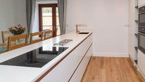 Une cuisine moderne dotée d’un îlot central, de chaises en bois, d’une table à manger et offrant une vue sur l’extérieur.