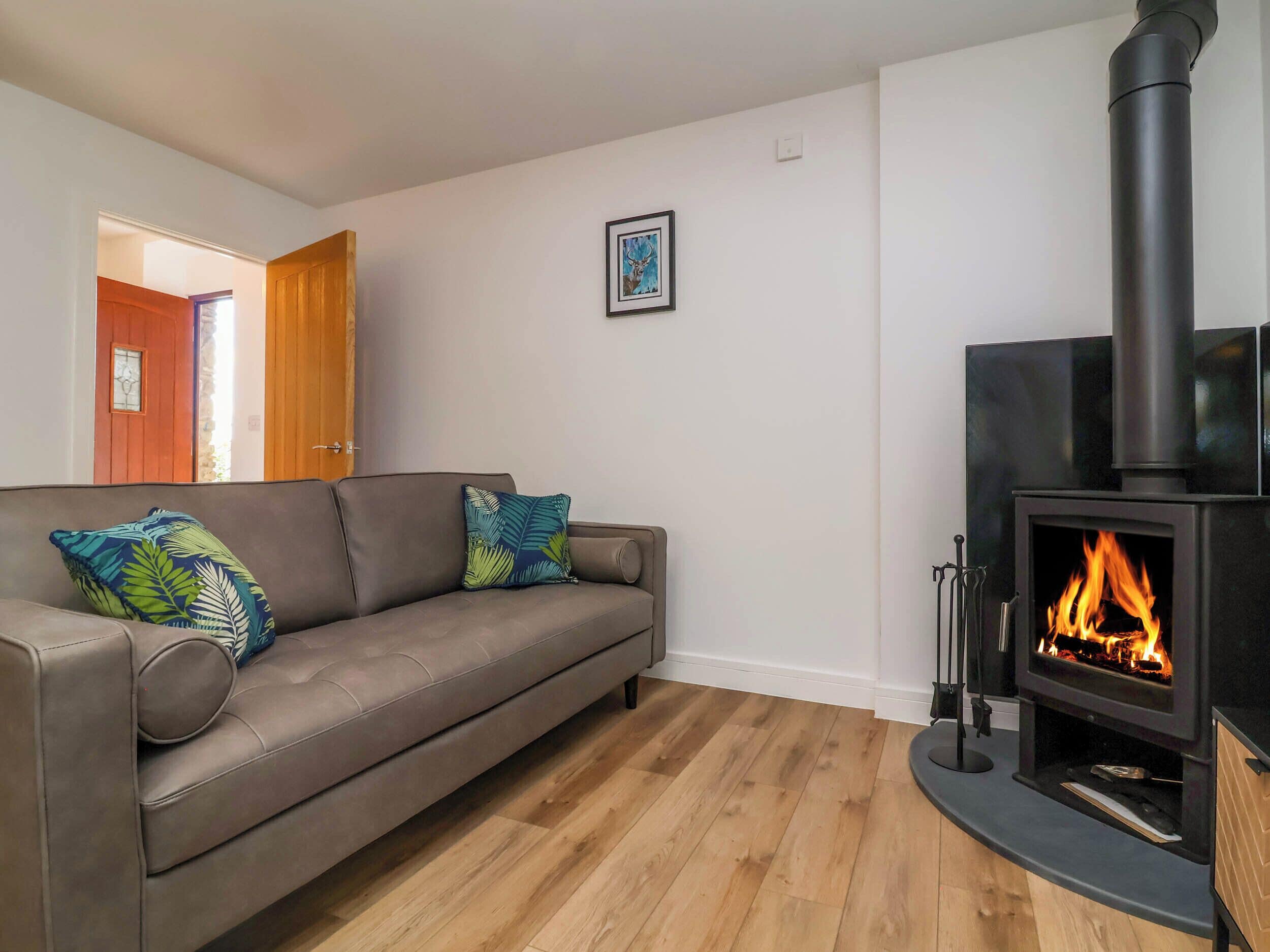 A living room with a sofa, a fireplace, and a wooden floor.