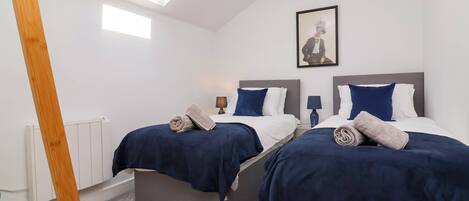 A hotel room with two beds, a skylight, a radiator, and a framed picture on the wall.
