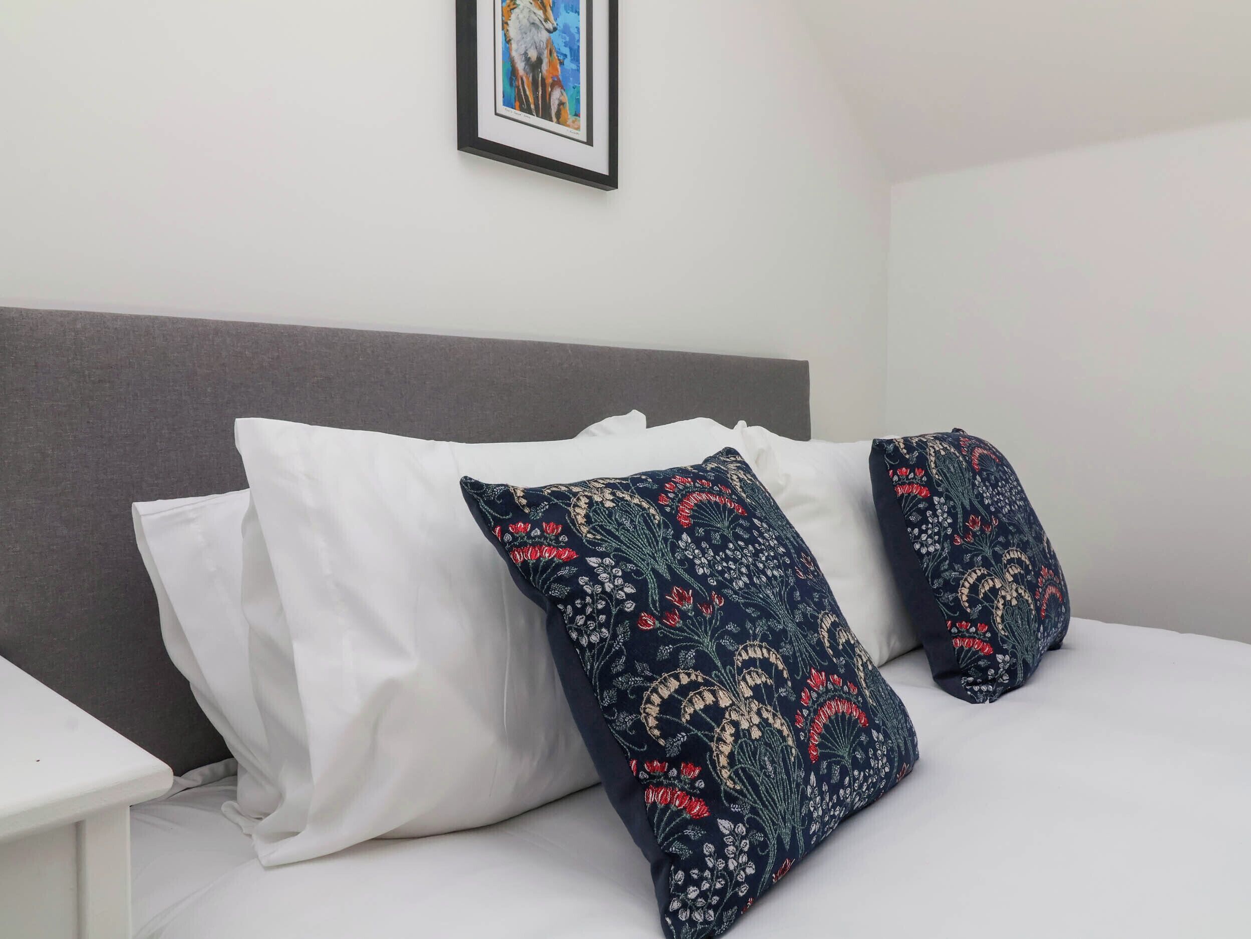 A bed with white bedding and two decorative pillows with floral patterns.
