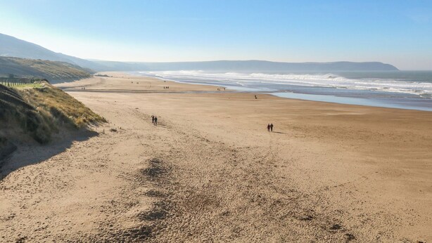Une vaste plage de sable fin, avec des vagues douces et un ciel dégagé.