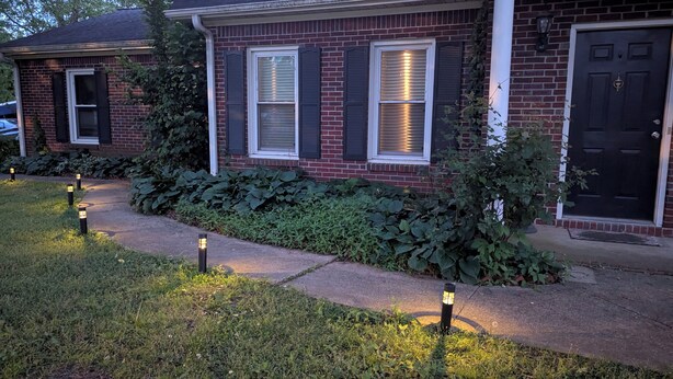 A residential house with a brick exterior, a front door, and a pathway leading to the entrance. - Moontown Magic (Huntsville)