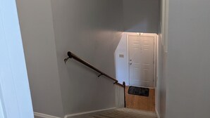 A carpeted staircase with a handrail, white walls, and a door at the top. - Moontown Magic (Huntsville)