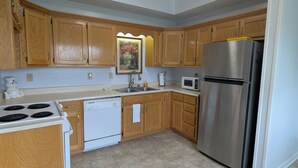 A kitchen with wooden cabinets, a stainless steel refrigerator, a microwave, a dishwasher, and a stove. - Moontown Magic (Huntsville)