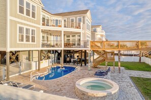 A two-story house with a swimming pool, a hot tub, and a deck overlooking a body of water. - Ocean Breeze: Oceanfront Pool & Hot Tub (Murrells Inlet)