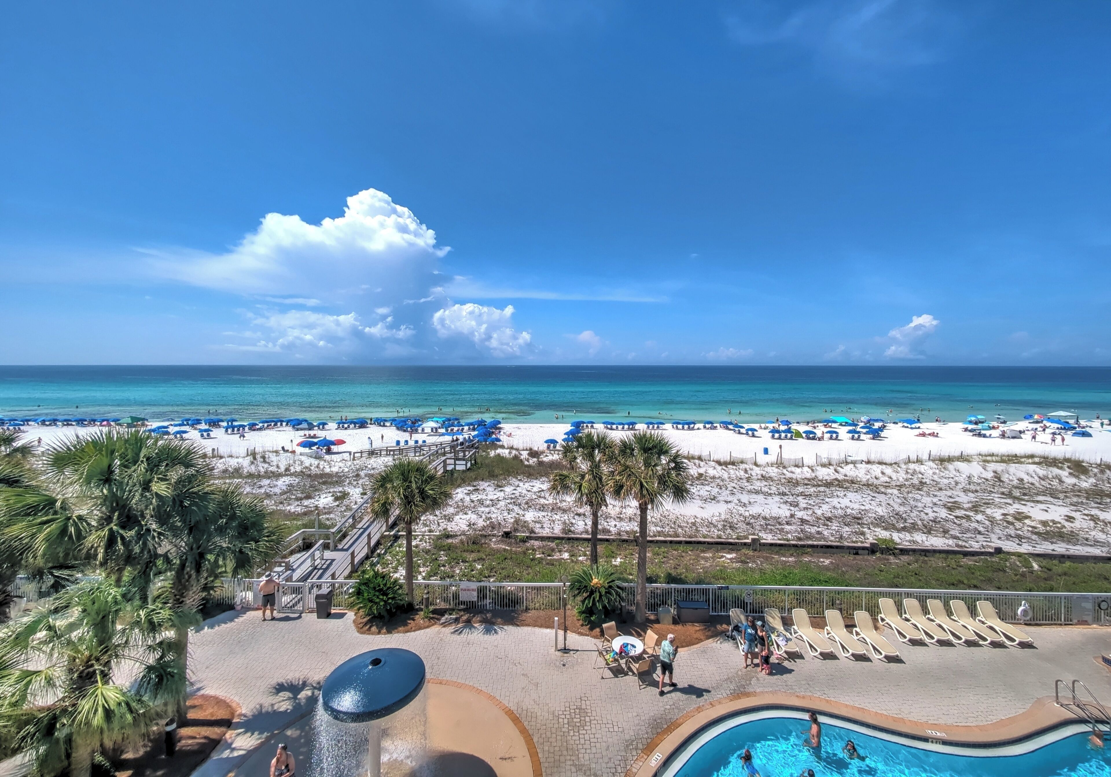 Ein Poolbereich eines Resorts mit Blick auf Strand und Meer.