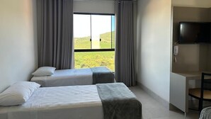 Een hotelkamer met twee bedden, een bureau en een televisie.