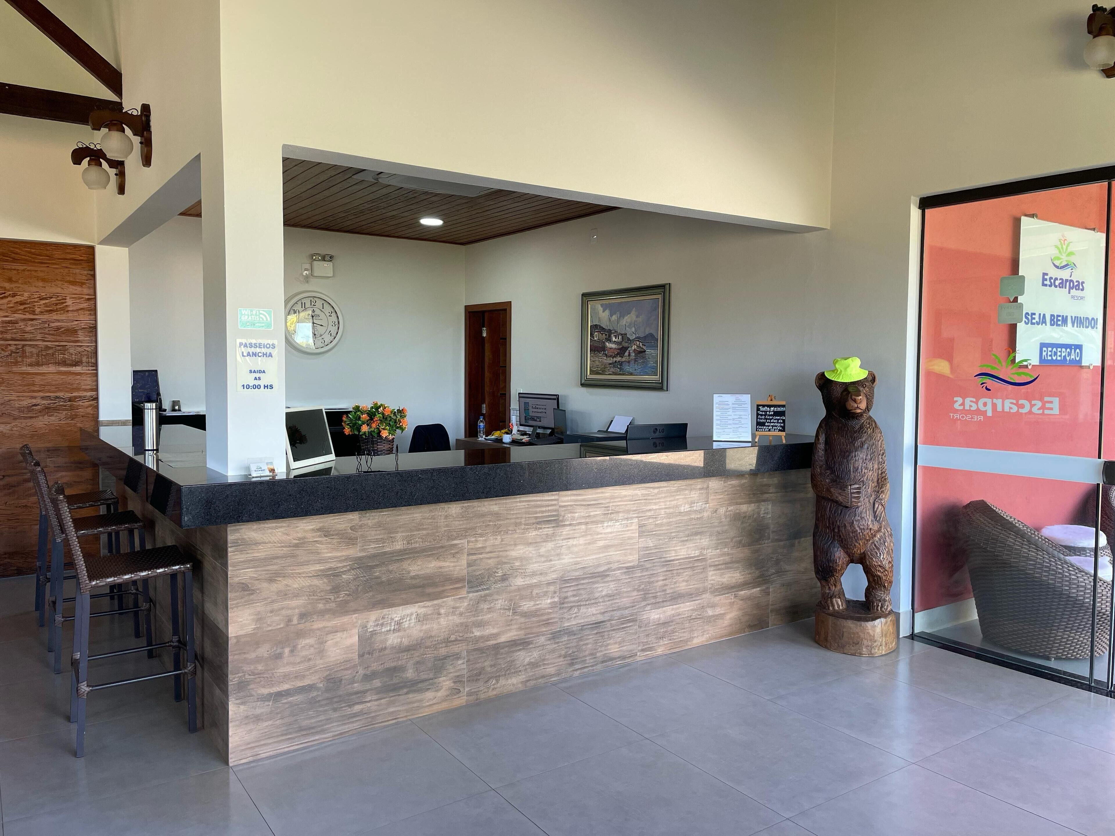 Una recepción con detalles de madera, un reloj, un cuadro enmarco y una estatua de madera.