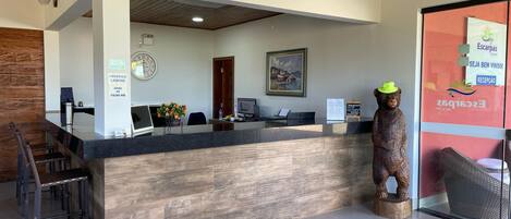 Una recepción con detalles de madera, un reloj, un cuadro enmarco y una estatua de madera.