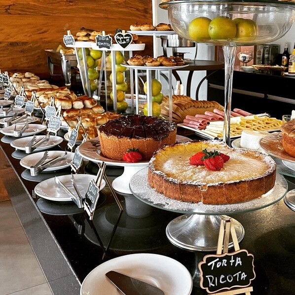 A buffet with various desserts and fruits, including cakes and a bowl of lemons. - Escarpas Resort (Capitólio)