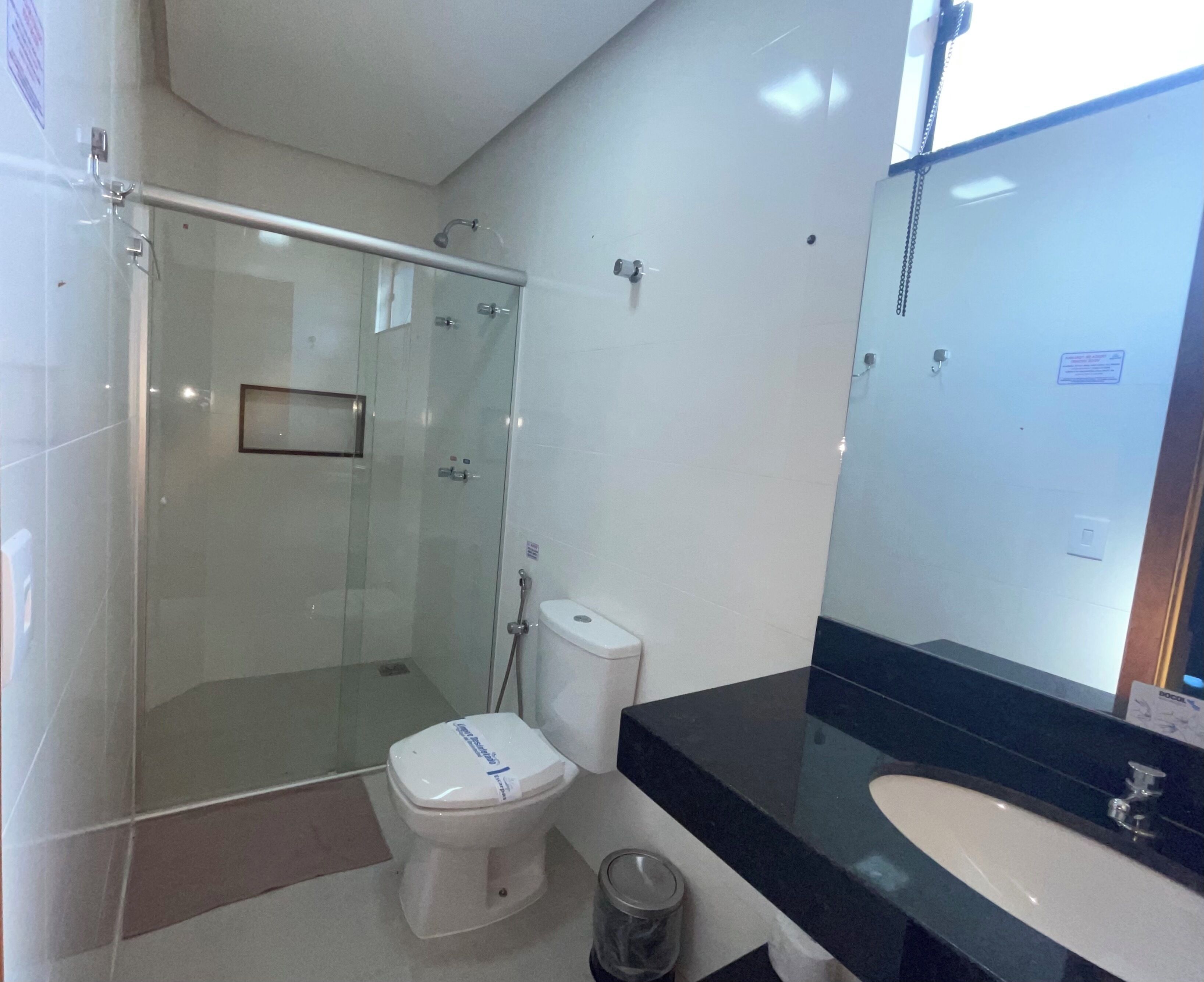 A modern bathroom with a glass-enclosed shower, a white toilet, and a black countertop with a sink.