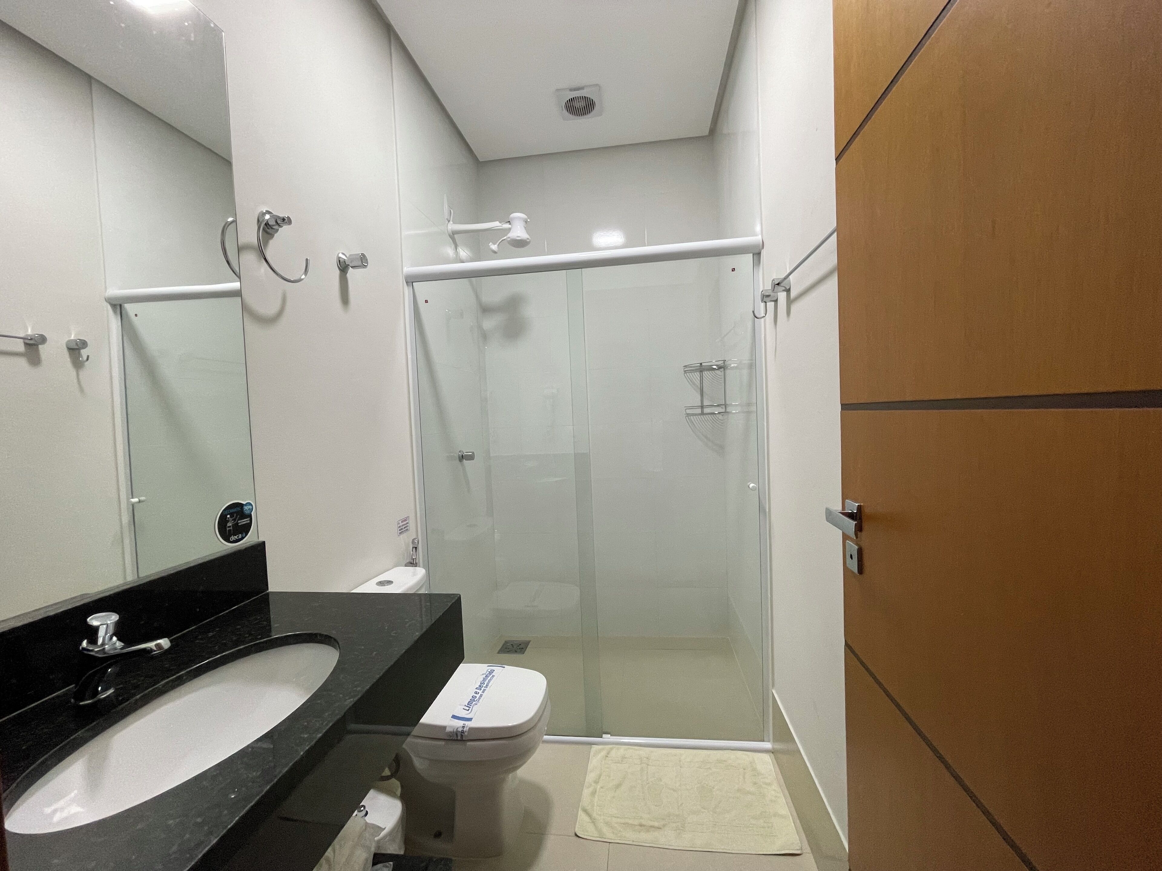 A modern bathroom with a black sink, white toilet, and glass shower enclosure.
