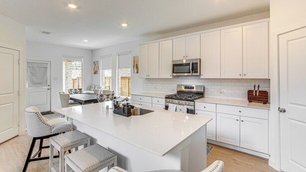 A modern kitchen with white cabinetry, a central island with bar stools, a built-in microwave, and a stove. - 8 Mi to Celebration Station: Family Getaway! (Mesquite)
