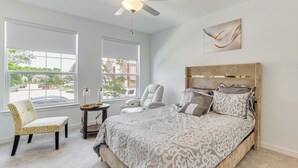 A bedroom with a large bed, a chair, a small table, and a ceiling fan. - 8 Mi to Celebration Station: Family Getaway! (Mesquite)