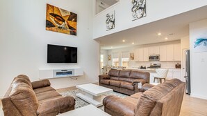 A modern living room with brown leather sofas, a white coffee table, and a flat-screen TV mounted on the wall. - 8 Mi to Celebration Station: Family Getaway! (Mesquite)