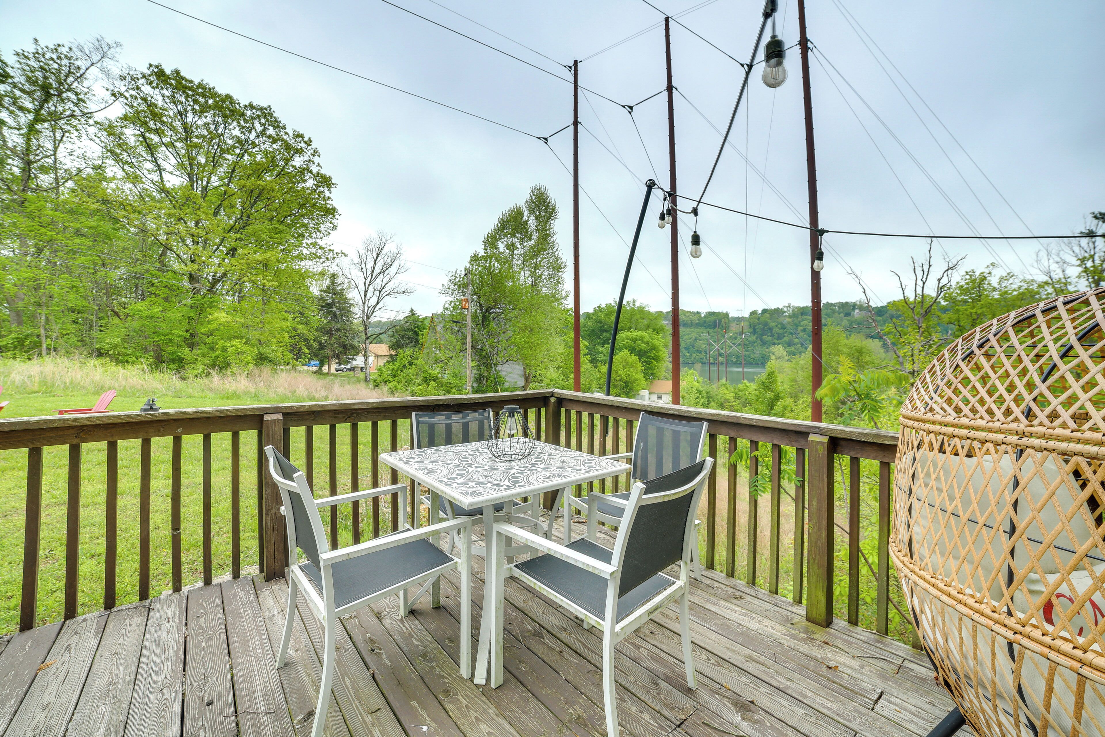 Une terrasse en bois avec une table et des chaises, donnant sur une pelouse et des arbres.
