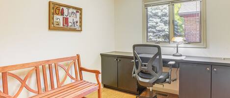 A room with a wooden bench, a desk with a chair, and a window with blinds.