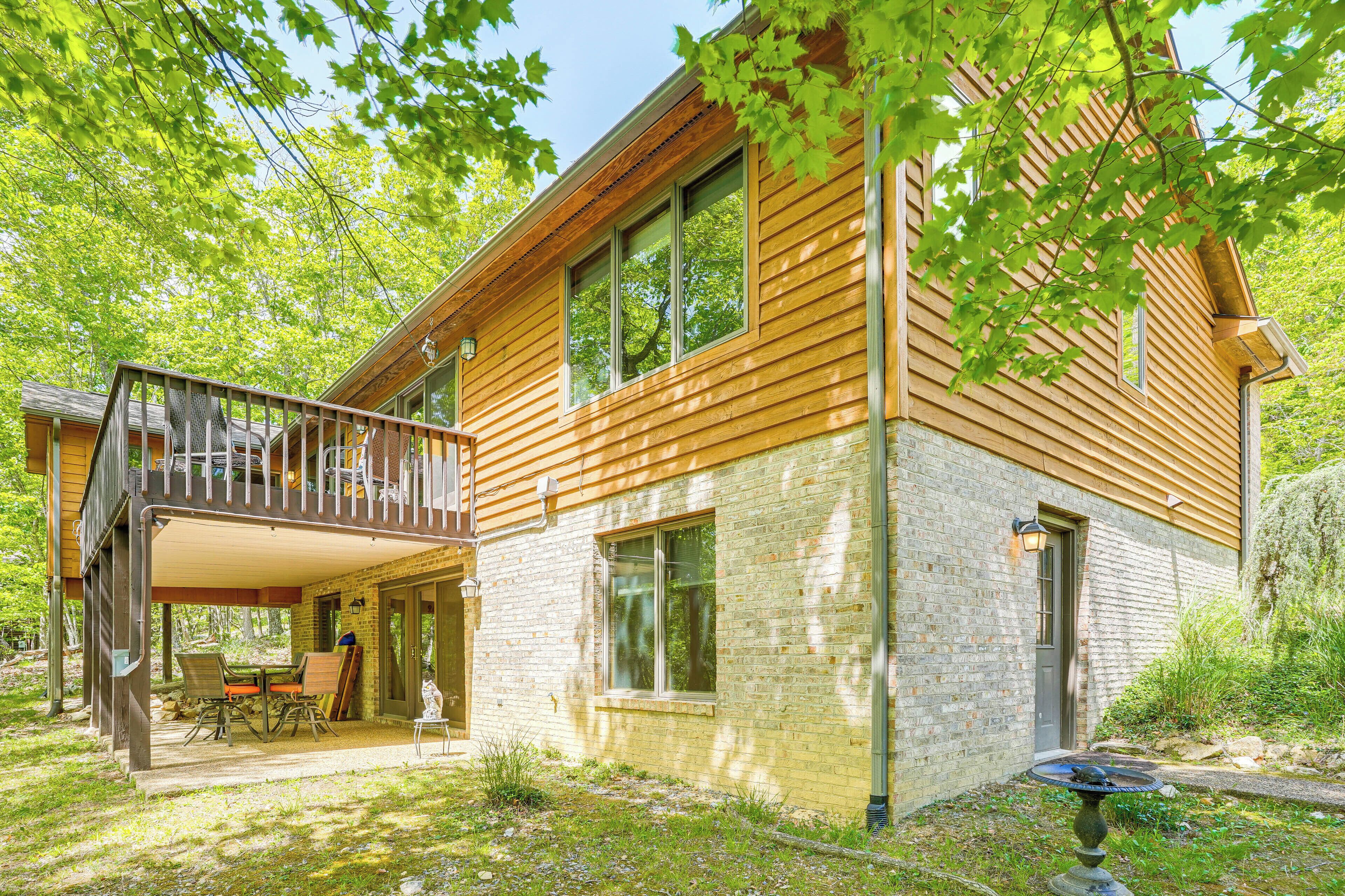 Une maison en bois à deux étages, dotée d’un balcon, d’une façade en briques et d’un petit jardin.