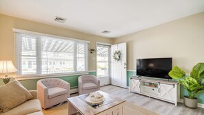 A living room with a sofa, two armchairs, a coffee table, a TV, and a potted plant.