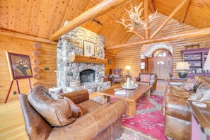 A log cabin interior with a stone fireplace, leather furniture, and a rustic decor. - Deck + Beach Access: Lakefront Cabin in Levering! (Levering)