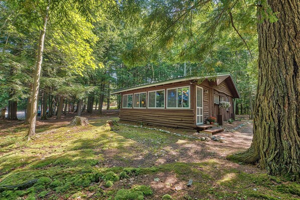 A log cabin with a wooden exterior, large windows, and a porch with steps leading up to the entrance. - Steps to Lakefront: Dog-friendly Cabin in Levering (Levering)