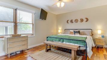 A bedroom with a bed, a bench, a dresser, a TV, and wall decorations.