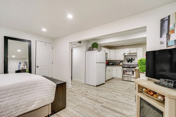 Un appartement moderne doté d’un grand lit, d’une kitchenette et d’un téléviseur.