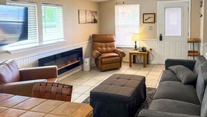 A living room with a fireplace, a brown leather armchair, a grey sofa, and a patterned rug. - Anglers Cabin on Lake Talquin < 1 Mi to Marinas (Quincy)