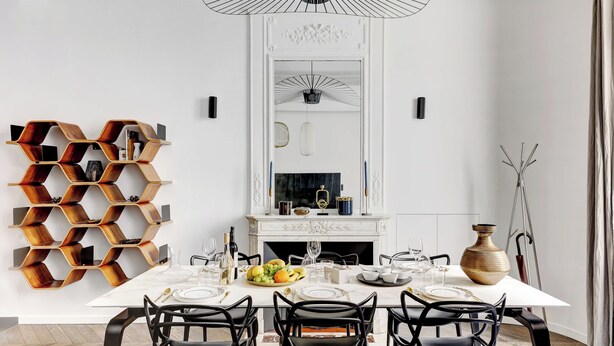 A dining room with a white table set for four, surrounded by black chairs, a decorative wooden shelf, and a fireplace with a marble mantle. - Luxury Apt - 4P/2BDR - Arc de Triomphe (Paris)