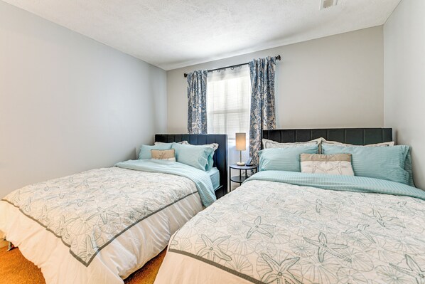 A bedroom with two beds, a nightstand, and a window with curtains. - Condo w/ Pool & Hot Tub in Aberdeen Golf Villas! (Longs)
