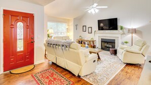 A living room with a red door, beige sofa, and a fireplace. - Deck & Yard: Savannah Area Retreat! (Pooler)