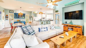 A spacious living room with a white sofa, wooden coffee table, and a ceiling fan. - Hot Tub & Bay Views: Outer Banks Home (Kill Devil Hills)