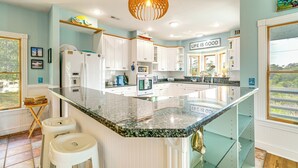 A modern kitchen with white cabinets, a granite countertop, and a hanging light fixture. - Hot Tub & Bay Views: Outer Banks Home (Kill Devil Hills)