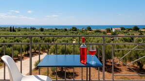 A balcony with a table, a bottle, and a glass of red wine. - Seaview Serenity - Beachside Getaway (Trifylia)