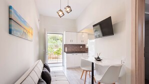 A modern kitchen with white cabinets, a white countertop, and a black TV mounted above the counter. - Seaview Serenity - Beachside Getaway (Trifylia)