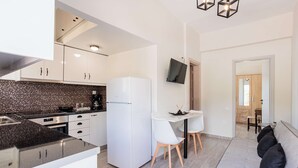 A modern kitchen with white cabinets, a white refrigerator, and a dining area with a white table and chairs. - Seaview Serenity - Beachside Getaway (Trifylia)