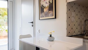 Une cuisine moderne avec un plan de travail blanc, un vase de fleurs et un mur recouvert de carreaux.