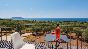 Un balcon avec une table, une chaise et une bouteille de vin rouge.